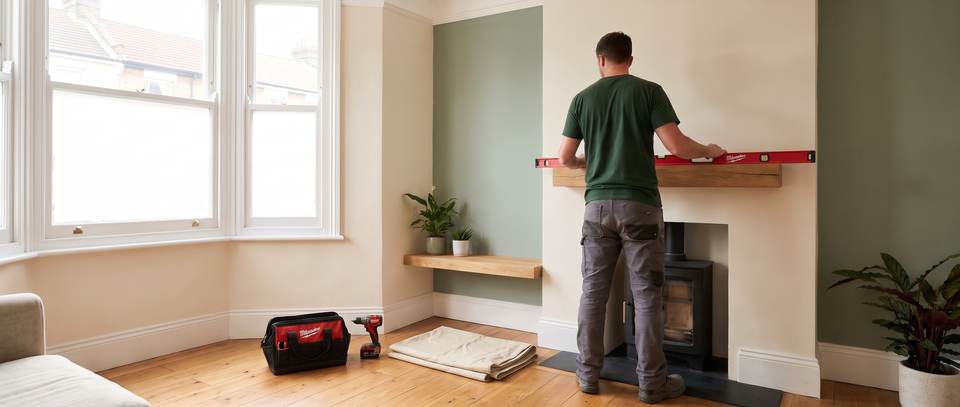 A tradesperson levelling a new oak shelf