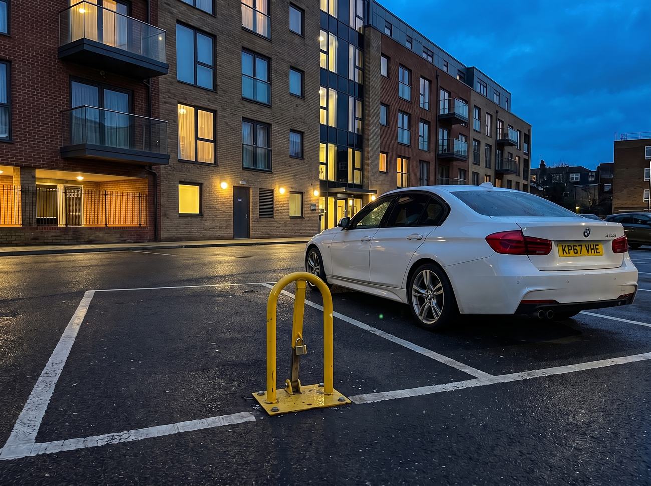 A padlocked fold-down parking post guarding an empty allocated bay